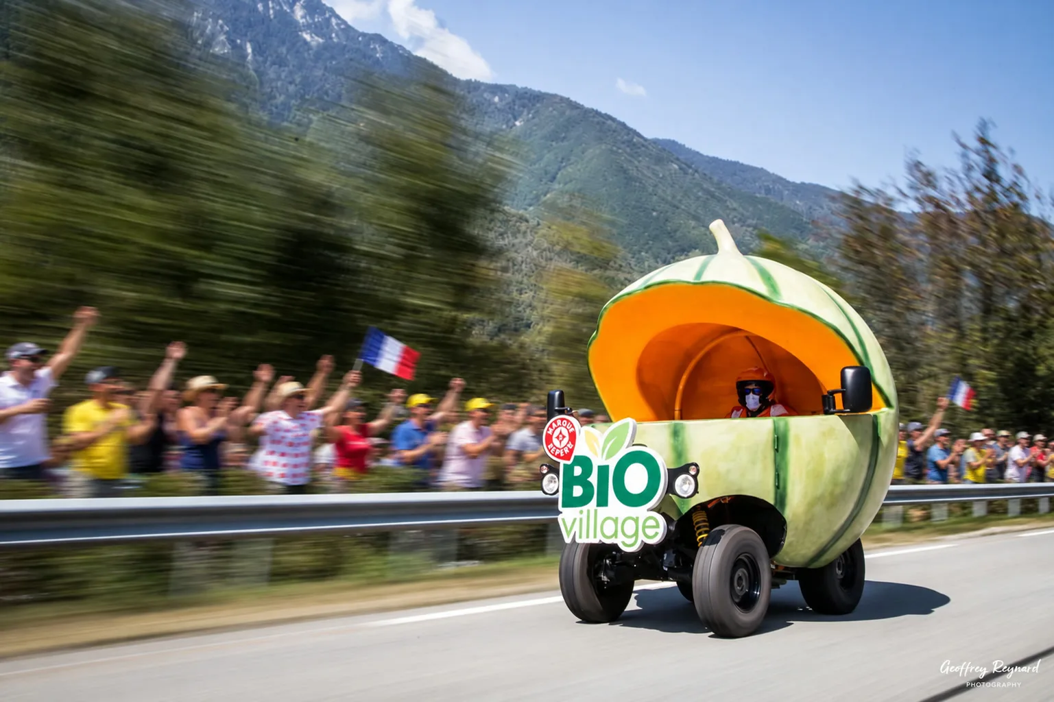 Véhicule promotionnel Bio Village sur la route, public en liesse