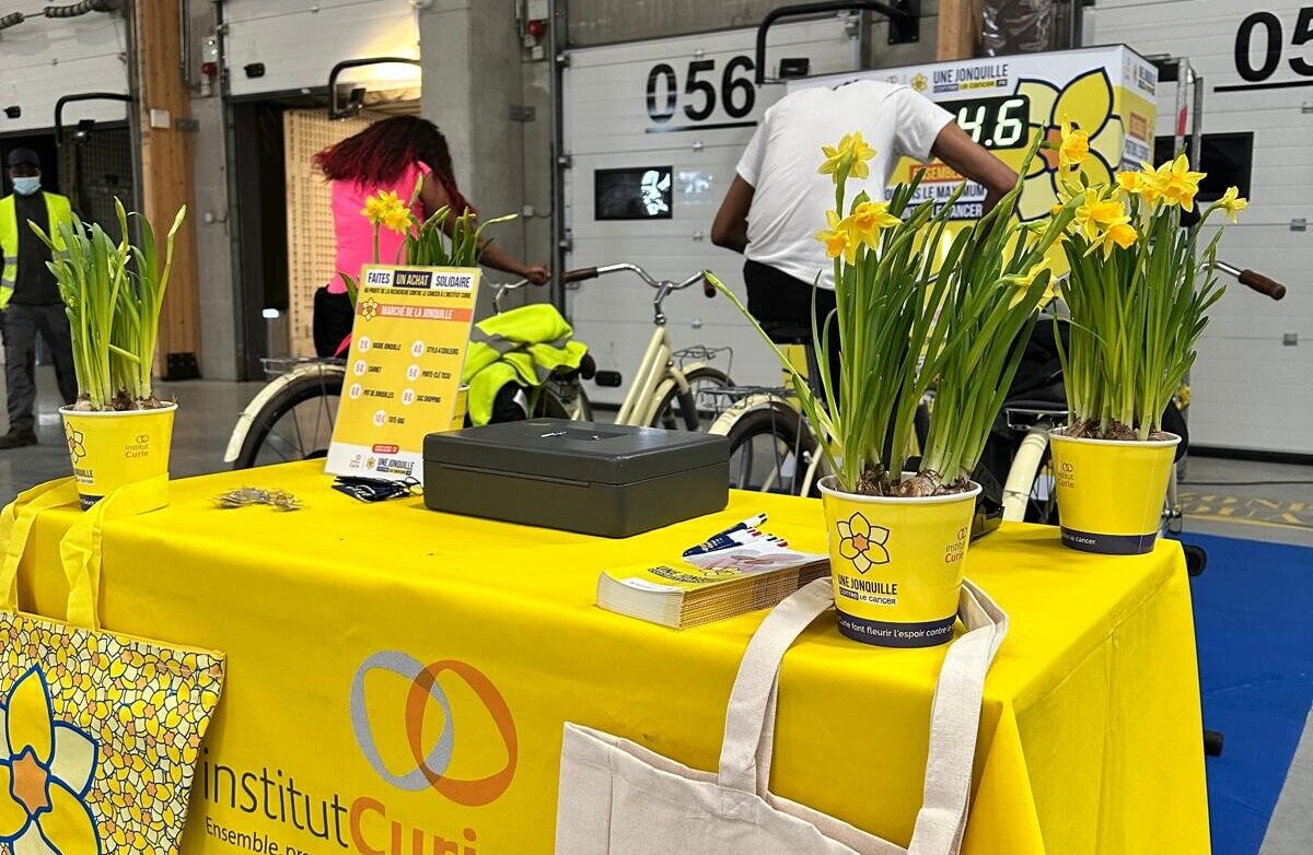 Stand Institut Curie : jonquilles, nappe jaune et sacs de l'opération