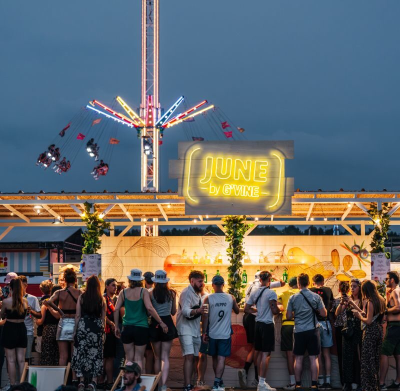 Bar JUNE by G'Vine de nuit, enseigne néon et manège du festival